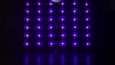 Bir kadın, arka planında renkli ışık duvarıyla Gece Kulübü 'nde profesyonel pop ya da hip hop dansı yapıyor. RNB Müzik Seksi Dans Performansı. Dark Stüdyo Sahnesi 4K 'de parlak sahne ışıkları.