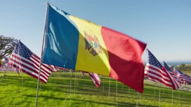 Andorra bayrağı rüzgarda dalgalanırken birçok Amerikan bayraklarıyla birlikte altın günbatımında güneş ışıldıyor. Ulusal Andorra bayrağı bağımsızlığı, mali ekonomiyi, iş ortaklığı 4K