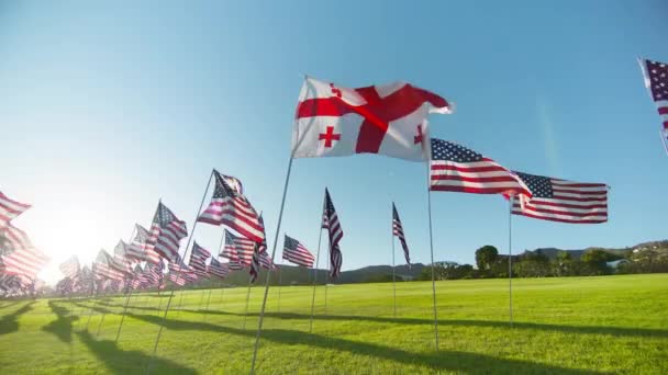 格鲁吉亚国旗在风中飘扬 许多美国国旗在金色落日和太阳耀斑的背景下飘扬 展示独立 金融经济 商业伙伴关系的格鲁吉亚国旗 — 图库视频影像