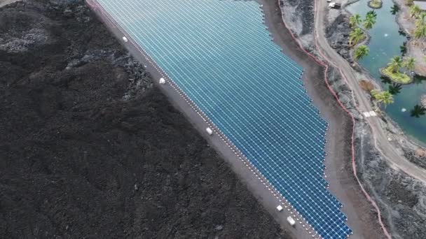 ハワイ州ビッグアイランドの黒い溶岩原での太陽光発電所の空中撮影4K 晴れた夏の日に太陽光発電所 青い太陽光発電所のドローンビュー コピースペース付き再生可能エネルギーコンセプト — ストック動画