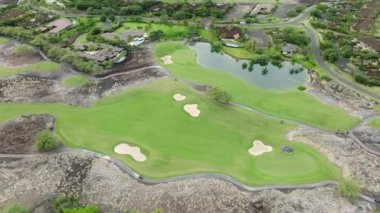 Beyaz kum tuzağı olan yeşil çimenler ve ağaçlar. İnsansız hava aracı golf sahasının üzerinde uçuyor ve pahalı otel 4K USA. Büyük Ada Hawaii 'deki yeşil bir golf sahasının havadan görünüşü, ABD yaz turizmi