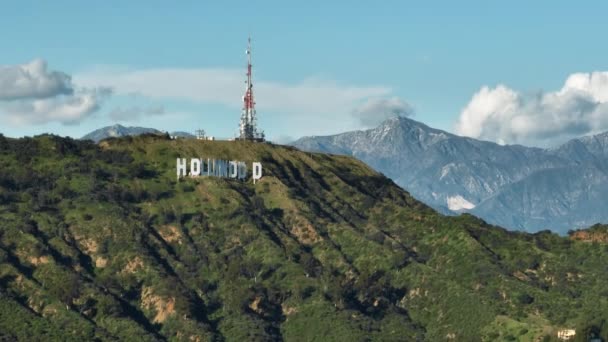 映画カリフォルニアのランドマーク有名なハリウッド映画の背景に山と晴れた夏の日に緑の丘にサインします ロサンゼルスの風光明媚な航空ヘリコプタービュー California Usa March 2023 — ストック動画