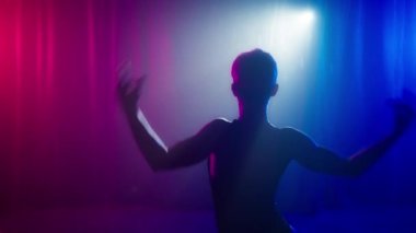 Stüdyo sanat çekimlerinde pembe ışık. Şehvetli model kızın gölgesi yavaşça hareket eder ya da neon kırmızısı mor ışıkta dans eder. Dans eden elleri olan güzel, seksi bir kadın vücudu.