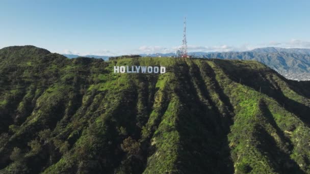 ハリウッドの素晴らしい景色バーバンクと高い山の頂上を背景に雲に覆われた美しい緑の丘にサインしてください 空中ヘリコプタービュー ロサンゼルス市カリフォルニア州2023年3月 — ストック動画