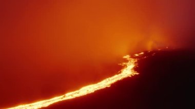 Hawaii Adası 'ndaki aktif volkan kraterinden akan lav nehrinin üzerindeki çılgın üstgeçit. Gece magma ve Mauna Loa dağının üstünde turuncu bulutlar parlıyor. İnanılmaz dramatik volkanik patlama
