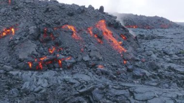 Turuncu lavın üzerinde uçan hava aracı magma aşağı akıyor ve siyah dağda donuyor. 2022 'de Hawaii, Büyük Ada' da Mauna Loa yanardağının sıcak lav akıntısı sinemalarda buharlaşıyor.