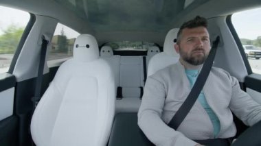 Güneşli yaz gününde otomatik pilot teknolojisini kullanan, Tesla Model Y 'nin içindeki olgun erkek sürücü. Çevre dostu, modern elektrikli araba kullanan yakışıklı bir adam. Tren yapay zeka sürücüsü sistem araçlarını izliyor