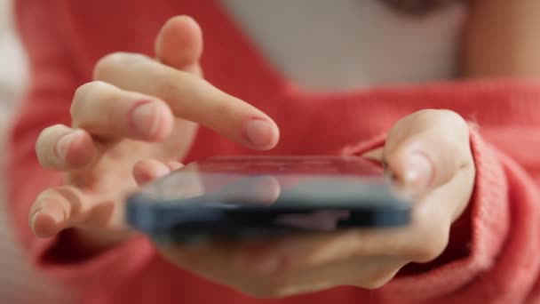 現代のスマートフォンの画面に触れる女性の指の映画的なクローズアップショット 女の子は携帯電話デバイス上のモバイルアプリでページをスクロールします オンラインで映画を見るためにインターネット図書館で映画ビデオを閲覧 — ストック動画
