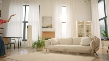 Evde saçlarını tarayan mutlu genç bir kadının Yavaş Hareketi. Çoklu etnik kız komik dans hareketleriyle kutluyor, hafta sonu sabah özgürlüğün tadını çıkarıyor, 4K çekim tarzı oturma odası.