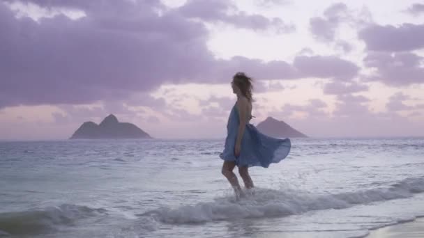 ハワイ島の夏休み 旅行の背景 幸せな女性が青い海に入っていく風景をバックにモクルア島とラニカイビーチ映画風の強い日の出 空のピンクの紫色の雲 — ストック動画