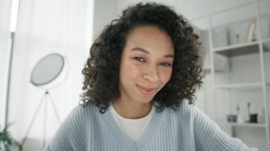 Genç mutlu Afrikalı Amerikalı vlogger kadın el sallayarak webcam 'e bakıyor ve kamerayla konuşuyor. Video konferansındaki karışık ırk hipster kızı sosyal mesafe arkadaşı 4K ile sanal sohbet görüşmesi istiyor.
