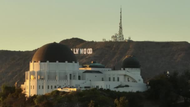 映画のような黄金の時間の日没の光でグリフィス天文台ドーム ハリウッド文字映画の背景に登場ハリウッドの看板の息をのむような航空機 ドローン ロサンゼルス カリフォルニア州2023年2月 — ストック動画