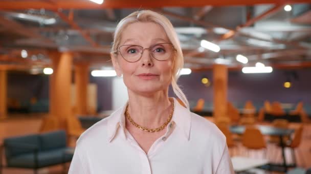 在视频会议电话中 50多岁的漂亮金发女人戴着眼镜与摄像头交谈 通过互联网连接技术与客户进行远程合同谈判 办公室录象电话 — 图库视频影像