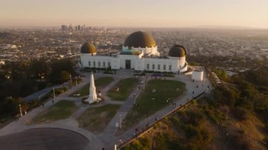 Los Angeles şehir merkezindeki hareketli arka planda dramatik günbatımı mercekleri parlıyor. Tepedeki Griffith Park gözlemevinin etrafındaki hava ve güneş ışınları. Seyahat varış yeri 4K LOS ANGELES, ABD Şubat 2023