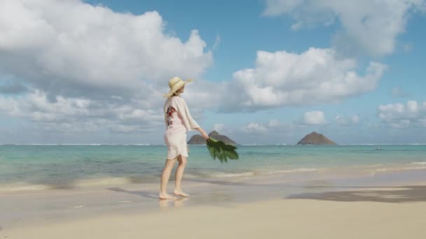夏の旅行休暇を楽しんでいる美しいアメリカの女性 幸せな笑顔遊び心の陽気な女の子オアフ島踊り 興奮し 喜びの女性はハワイ島の赤い水着 ビーチカバー わら帽子を身に着けている — ストック動画