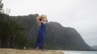 Kırmızı kamera panorama, seyahat eden bayanı çekiyor. Çiçekli kolyesiz, Oahu 4K manzaralı. 30 'lu yaşlardaki otantik gezgin kadın mor Maxi Boho tarzı elbise giymiş Hawaii plajı manzarasının keyfini çıkarıyor.