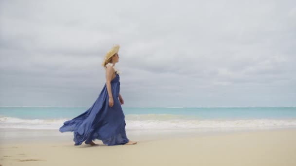 夏休みに美しい飛行紫色のブーブースタイルのドレスで幸せな女の子 ロマンチックなビーチドレスでエレガントな女性30代美しい海の背景で白い砂浜の海岸を歩く潮風で平坦化 — ストック動画