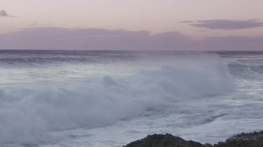 Güzel deniz arka planı, yavaş çekim RED kamera görüntüsü. Rocky Beach Oahu adası, Hawaii vahşi doğası, seyahat tutkusu ABD. Karanlık, sakin deniz dalgaları sıçramalarla çarpıyor, akşam üstü alaca karanlık gökyüzü.