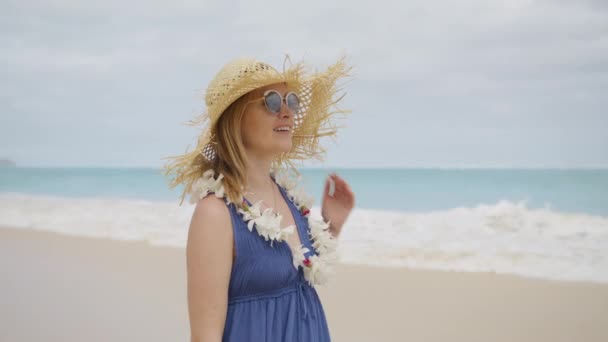 幸せな女性の花のレイと空想のわらの帽子をかぶって ハワイの島の巡航 オアフ島4K 夏休みにビーチを歩いている間に笑顔Bohoスタイルの紫のドレスで美しい若い女性の肖像 — ストック動画