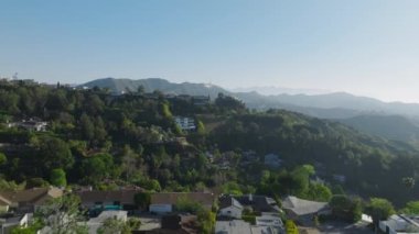 Güneşli bir sabahta Los Angeles Hollywood Hills 'te büyük lüks gayrimenkul evleri. Güneşli bir bahar gününde Los Feliz bölgesi. Hollywood tabelası mavi gökyüzünün altındaki yeşil tepelerde görüldü.