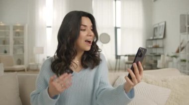 Kocasıyla, erkek arkadaşıyla ya da akrabalarıyla kanepesinde selfie ya da video görüşmesi yapan otantik, mutlu, zarif bir kadın. Modern teknoloji kavramı, aile yavaş çekim 4K video ile kablosuz bağlantı