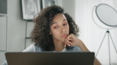 Üzgün Afrikalı iş kadını bilgisayarını bitiriyor ve dizüstü bilgisayarını kapatıyordu. Bitmemiş projeyle ilgili derin düşüncelerini başka tarafa çeviriyordu. İşyerinde oturuyordu.