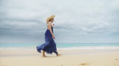 30 'lu yaşlarda romantik plaj elbisesi içinde güzel okyanus arka planında beyaz kum kıyısında yürüyen romantik bir kadın. Mutlu kız yaz tatilinde güzel mor boho tarzı elbiseler giyiyor.