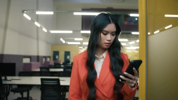 携帯電話を使用してオフィスのドレスコードスーツを身に着けている懸念アジアのビジネス女性は テキストメッセージや悪いニュースとビジネス電子メールフォームパートナーを受信します オープンスペースのビジネスオフィスの中を歩くSlowmo — ストック動画
