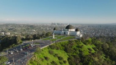 Griffith Gözlemevi Kubbeleri, güneşli bir yaz gününde, Hollywood Dağı 'ndaki yeşil parkta mavi gökyüzünün altında nefes kesici bir manzara. Çim gözetleme güvertesi antenine giriş. Los Angeles şehri Kaliforniya ABD Mart 2023