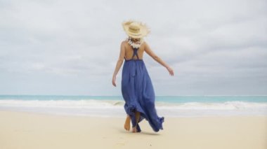 Moda tarzında boho tarzı yaz tatili yapan mutlu kız. Arkaya bakan romantik mor boho maxi elbiseli kadın deniz esintisini pohpohluyor tropikal sahilde yürüyor güzel okyanus arka planında