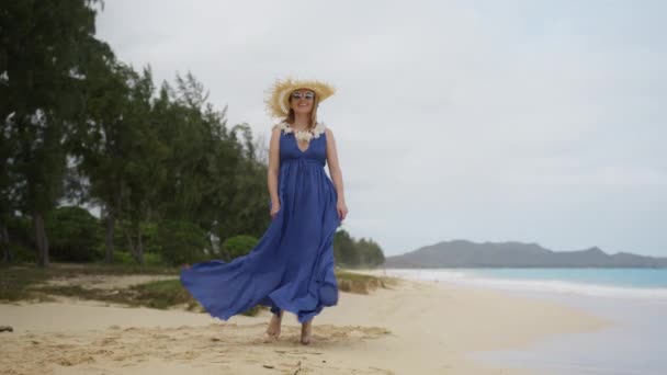 風光明媚なオアフ島の自然とレイフラワーネックレス歩くと旅行者の女性のレッドカメラの風光明媚なショット 30本物の旅行者女性でパープルマキシBohoスタイルのドレスとわら帽子楽しむハワイのビーチ4K — ストック動画