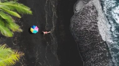 Güneşli bir günde gökkuşağı şemsiyesinde güneşlenen seksi kadın havası. Hawaii Adası 'nda yaz tatilindeki kadın turist. Seksi kırmızı mayolu mutlu kadın 4K drone