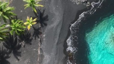 Hawaii siyah lav kumsalı. Büyük Ada 'da açık mavi deniz lagünü suyu var. Hawaii USA 'de güzel bir sahil şeridine ait 4K insansız hava aracı videosu. İnsansız hava aracı manzaralı güzel yeşil palmiye ağaçları