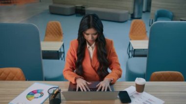 Odaklanmış Asyalı kadın 20 'li yaşlarda yönetici iş kadını masa başında oturuyor çağdaş çatı katında dizüstü bilgisayarda çalışıyor, sandalyeye yaslanıyor ve yorgun sırtı gerip ellerini başının arkasına koyuyor 4K