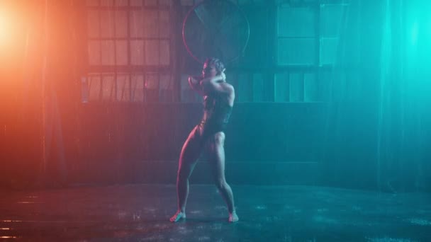 未来的なスタイルの4K背景スローモーション 鉄オレンジの光の中でサイバーパンクの女性は グランジスタイルのガレージ鋼空間に雨を注ぐの下で踊っている 濡れセクシー女性移動魅力的なパフォーマンスRedカム — ストック動画