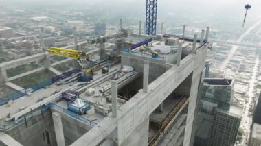 Gökdelen çatısında ağır makineler ve inşaat işçileri var. Mühendislerden oluşan çeşitli mimarlar ve inşaatçılardan oluşan farklı bir ekiple yeni inşaat alanının üzerinde havadan uçuş.