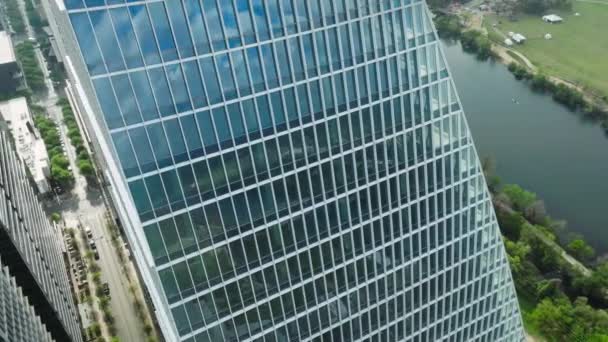 コロラド川のウォーターフロント4Kでのシネマティックガラスコンクリートデザインアパートの建物 現代のダウンタウンのオースティン建築 夏の空中 現代テキサスの都市景観ドローンBロール映像を見る — ストック動画