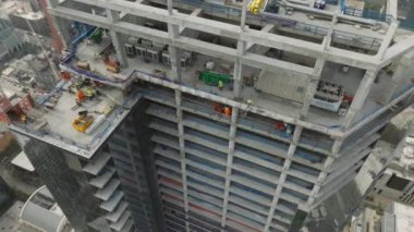 Austin 'deki yeni inşaat alanının üzerinde gökyüzü ve yüksek kule vinç inşaatı var. Ağır makineler ve inşaat işçileri mülk inşa ediyor. Üstten aşağı görüşlü müteahhitler.