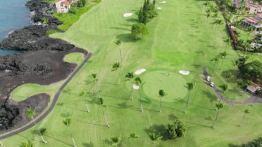 Hawaii sahili Big Island USA 'da golf oynayan insanların hava görüntüleri. Güneşli bir yaz gününde golf oynayan aktif erkeklere tepeden bakıldığında sinematik bir bakış. Arka plan golf işi.