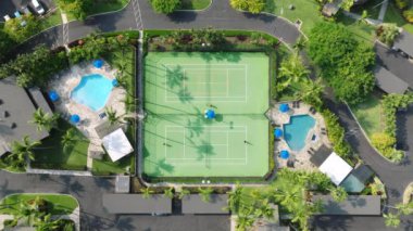 Sahada koşan aktif oyuncular ve raketlerle top atan Hawaii manzaralı 4K tenis maçı manzaralı. Güneş batarken tenis antrenmanı yapan atletik insanlar tropikal cennet yeşil adasında