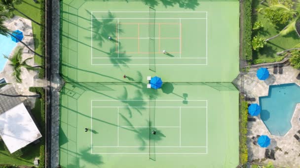 4K空中俯瞰运动员在网球练习期间 情侣们在阳光明媚的夏日以度假胜地的风格居住在网球场上 用网球拍打网球和跑美国的人 — 图库视频影像