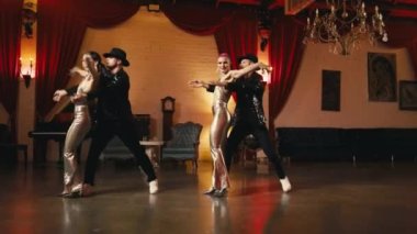 Bir grup stil sahibi genç insan senkronize koreografi ile dans ediyor, göz alıcı gece klübü mekanlarında parlak, şık kıyafetlerle dolaşıyorlar. Funk şov gösterisi. Modern profesyonel dansçılar yavaş çekim.