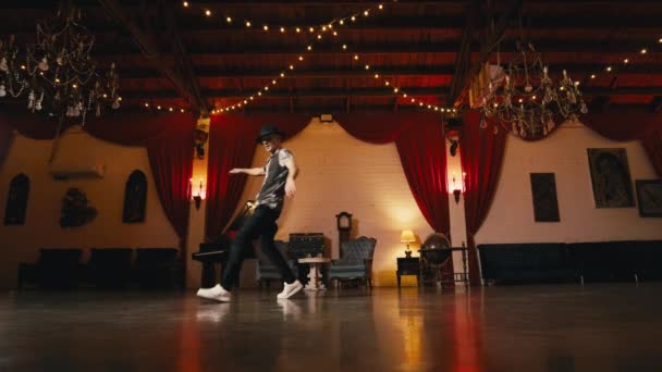 スタイリッシュな帽子で男を踊る床の回転を行うフリースタイルのダンスは室内で勝利スタイルの古典的なホールで楽しんでいます ヴィンテージレトロなライフスタイルの幸福コンセプト 男ブレイクダンスストリートヒップホップダンス — ストック動画