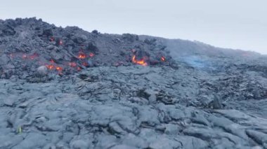 Siyah kömürde dumanla uçuşan ve donan kırmızı lav insansız hava aracının 4K hava görüntüsü. Pasifik Okyanusu 'ndaki Hawaii Adası' ndaki aktif volkanın duman yüzeyi.