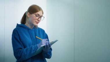 Beyaz kadın veteriner portresi kağıt panoya not alıyor ve veteriner kliniğinde gülümseyen kameraya bakıyor. Tıbbi iş konsepti kopya arka plan. Zeki profesyonel kadın 4K