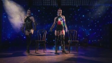 Seksi kadın striptizciler, tiyatro sahnesinde ya da gece kulübünde müşterilerini erotik dansla baştan çıkarıyorlar. Siyah iç çamaşırlı iki kadın popolarını göstererek ve aşağı inerek şehvetle hareket ediyor. Kabare konsepti 4K
