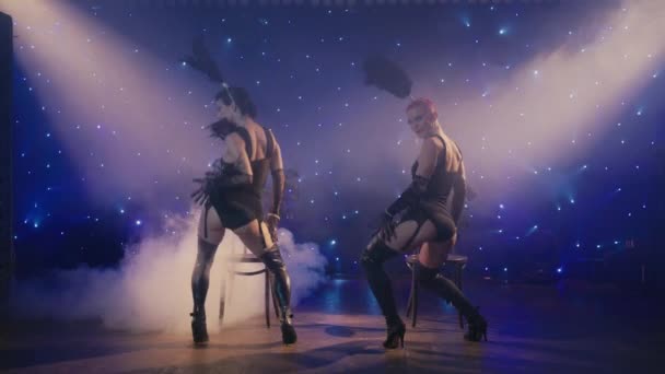 黒の下着の衣装を着た2人の女性は 官能的に下に下げ バットを示して移動します キャバレーのコンセプト4K セクシー女性Burlesqueダンサー魅力クライアントによってエロティックダンスオン劇場ステージまたはナイトクラブ — ストック動画