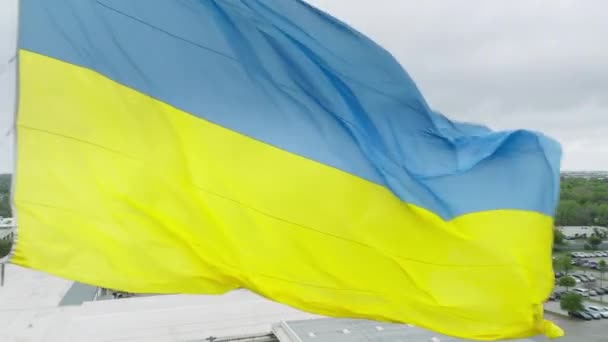 ウクライナのフラグの背景を振っての航空ズームアウト ウクライナのファブリックテクスチャフラグのマクロビューを閉じます ポール上の空の青と黄色の国家色のウクライナのバナー アメリカ国旗国章 — ストック動画