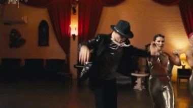 Modern funk caz koreografisinin elementleri genç dansçı çiftler tarafından klas retro stüdyo arka planında sahneleniyor. Erkekler ve kadınlar tutkulu bir şekilde dans ediyor, duygularını yavaş çekimde ifade ediyorlar.