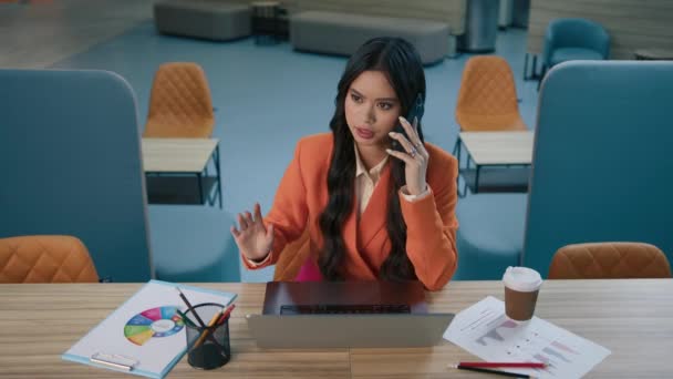 年轻的亚裔美国女性小企业主在与客户或合作伙伴的智能手机合作的开放空间办公室 与在笔记本电脑上工作的卖主争论不休的多种族亚裔女人烦躁不安 — 图库视频影像